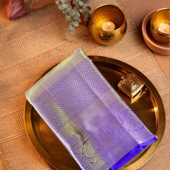 Decorative purple and gold saree on a gold tray with candles and plants in the background