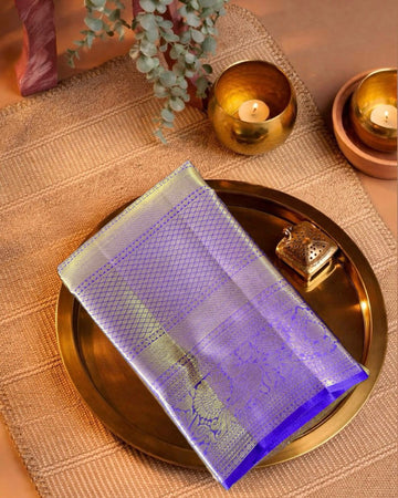 Decorative purple and gold saree on a gold tray with candles and plants in the background