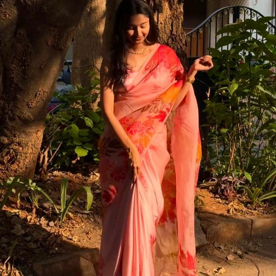 Woman in a pink saree standing outdoors near a tree