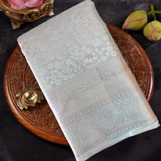 Light blue embroidered fabric on a dark surface with decorative elements