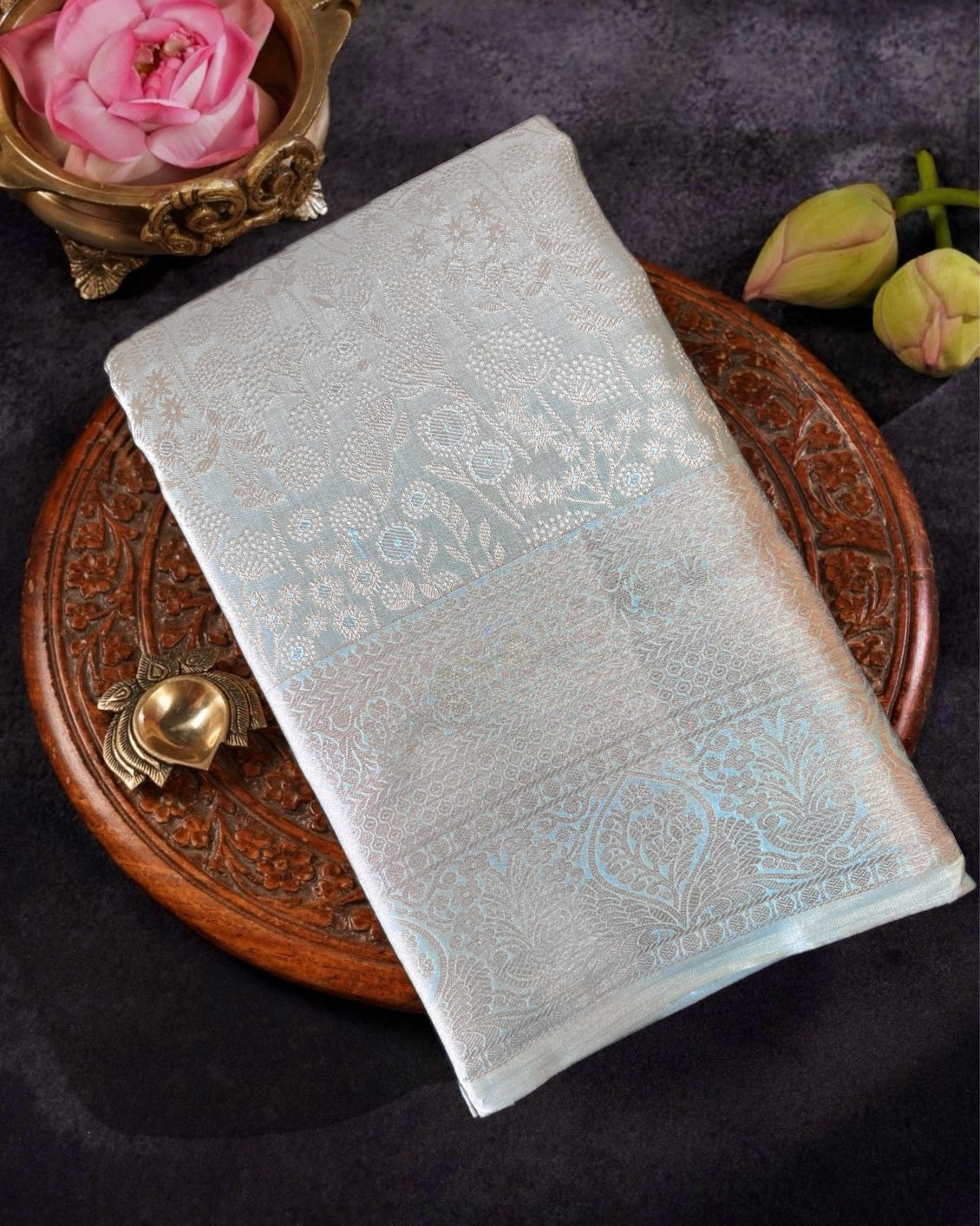 Light blue embroidered fabric on a dark surface with decorative elements